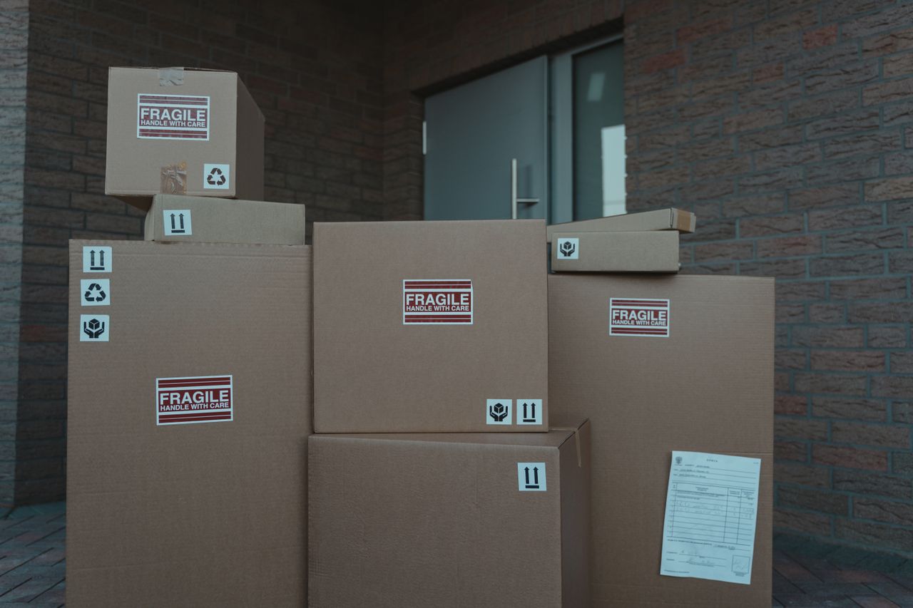 Several cardboard packages marked as fragile stacked at a building entrance.